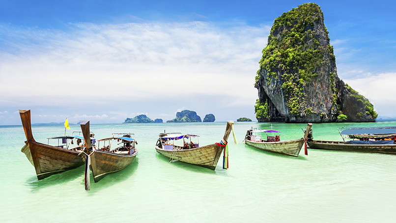 Longtail boats moored beside limestone cliffs