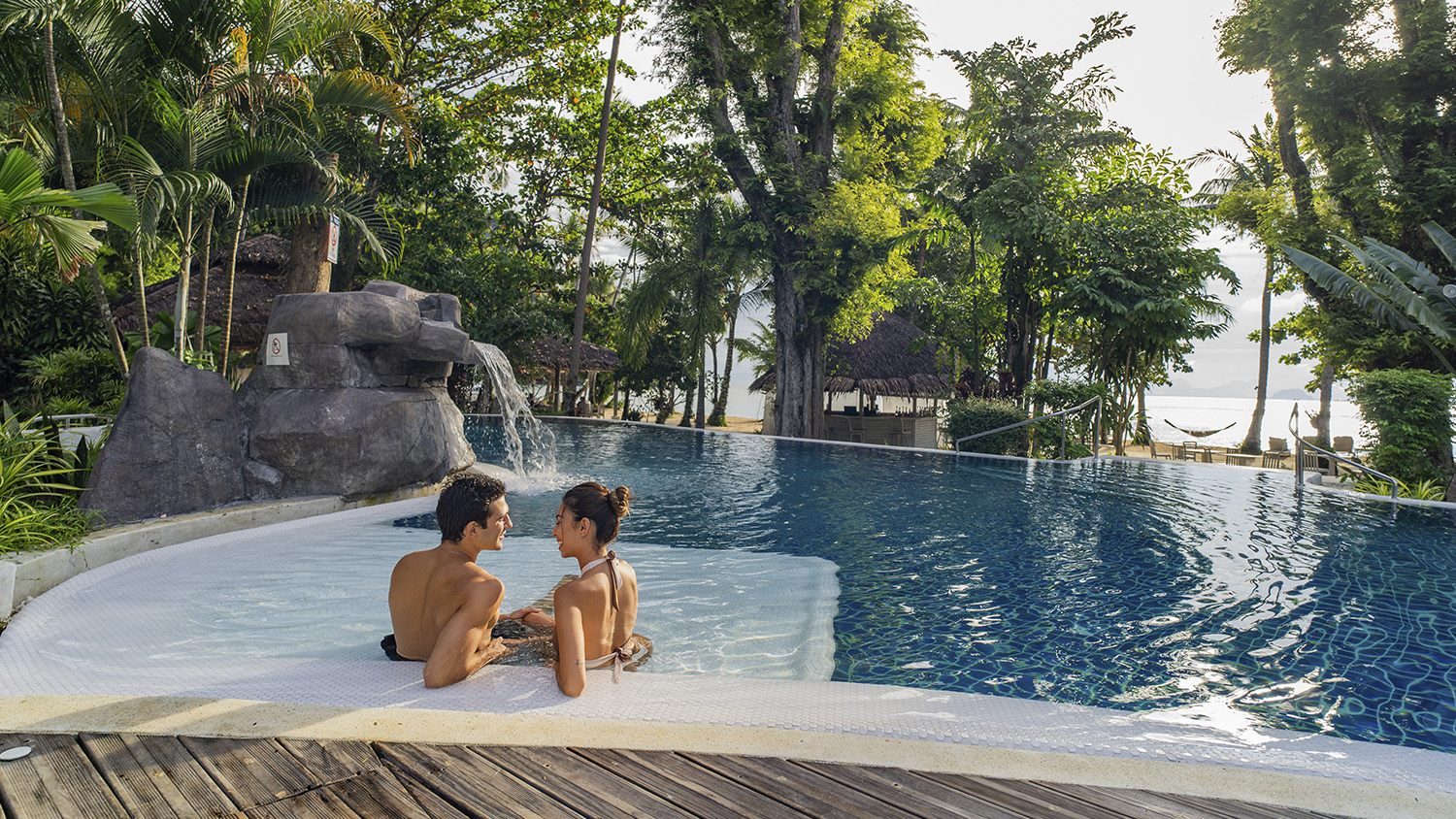 Couple in the pool's shallow shelf at sunset